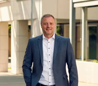 Mann im geschäftlichen Kontext, stehend vor einem Gebäude