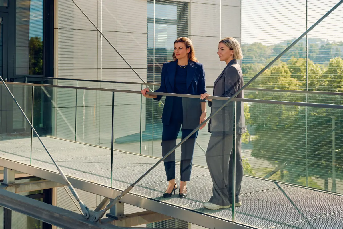 Zwei Frauen auf einem erhöhten Durchgang beziehungsweise Balkon, in die Weite schauend